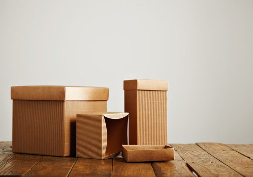 unlabeled similar boxes different shapes sizes uneven wooden table isolated white